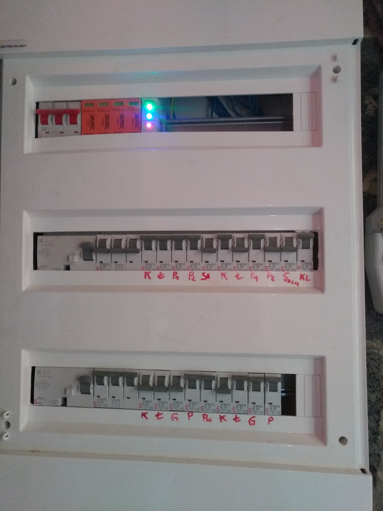 Rozdzielnica elektryczna z zabezpieczeniami przepięciowymi i wyłącznikami w Zawierciu, z ręcznie naniesionymi oznaczeniami obwodów.