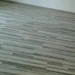 Ułożona podłoga z paneli imitujących drewno w odcieniach szarości i beżu, widok z góry pod kątem.