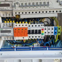 Rozdzielnica elektryczna z zabezpieczeniami przepięciowymi i licznikiem energii w Dobre, widoczne okablowanie i elementy montażowe.