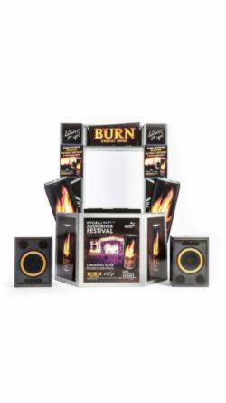 Ekspozytor promocyjny marki Burn z elementami graficznymi przedstawiającymi płomienie i napisy 'Light It Up', ustawiony na białym tle, z dwoma głośnikami po bokach.