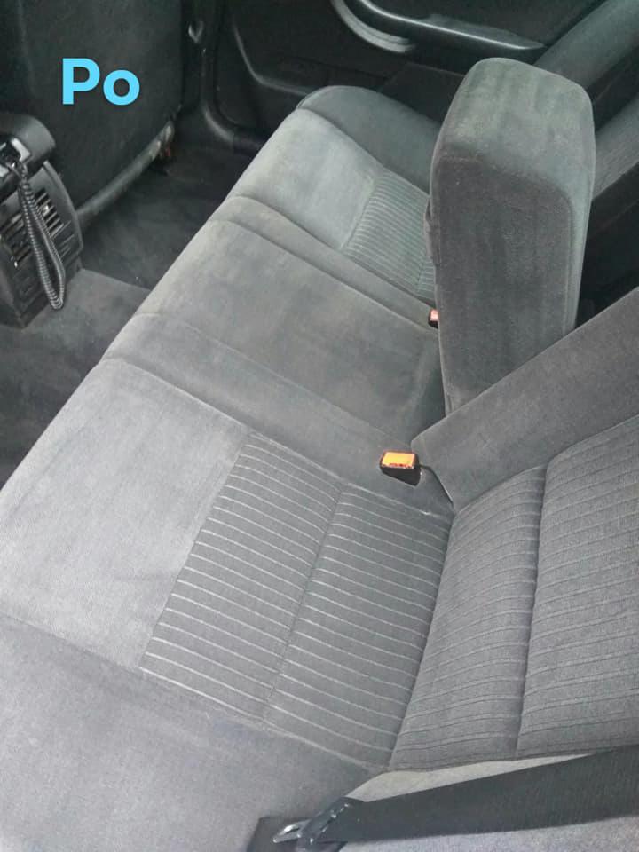 Szare, materiałowe siedzenia samochodowe z widocznymi pasami bezpieczeństwa, po czyszczeniu, widoczne delikatne wzory na tapicerce.