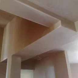 Świeżo położone tynki na ścianach i suficie z widocznymi detalami architektonicznymi wewnątrz pomieszczenia. Gładkie wykończenie, jasne kolory.