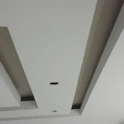 Nowoczesny sufit podwieszany z oświetleniem punktowym i geometrycznym układem kasetonów, wykonany w jasnej kolorystyce.