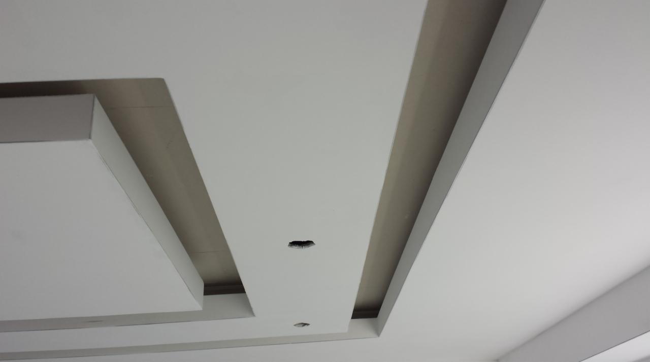 Nowoczesny sufit podwieszany z oświetleniem punktowym i geometrycznym układem kasetonów, wykonany w jasnej kolorystyce.