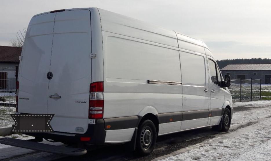 Biały samochód dostawczy Mercedes Sprinter na tle zimowego krajobrazu, widok z tyłu i boku, z widocznymi elementami karoserii i oponami.