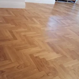 Parkiet ułożony we wzór jodełki, po renowacji z widocznym połyskiem, jasne listwy przypodłogowe