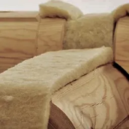 Fragment drewnianej konstrukcji domu z bali z widoczną wełną mineralną jako izolacją termiczną, detale połączeń między balami.