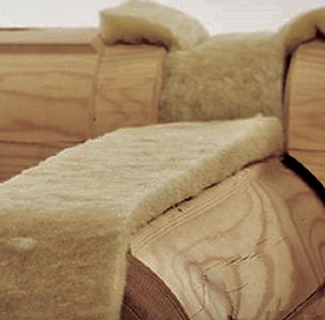 Fragment drewnianej konstrukcji domu z bali z widoczną wełną mineralną jako izolacją termiczną, detale połączeń między balami.