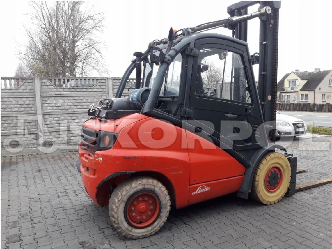 Czerwono-czarny wózek widłowy marki Linde na kostce brukowej, widoczny z boku, z lekko zużytą powłoką lakierniczą.