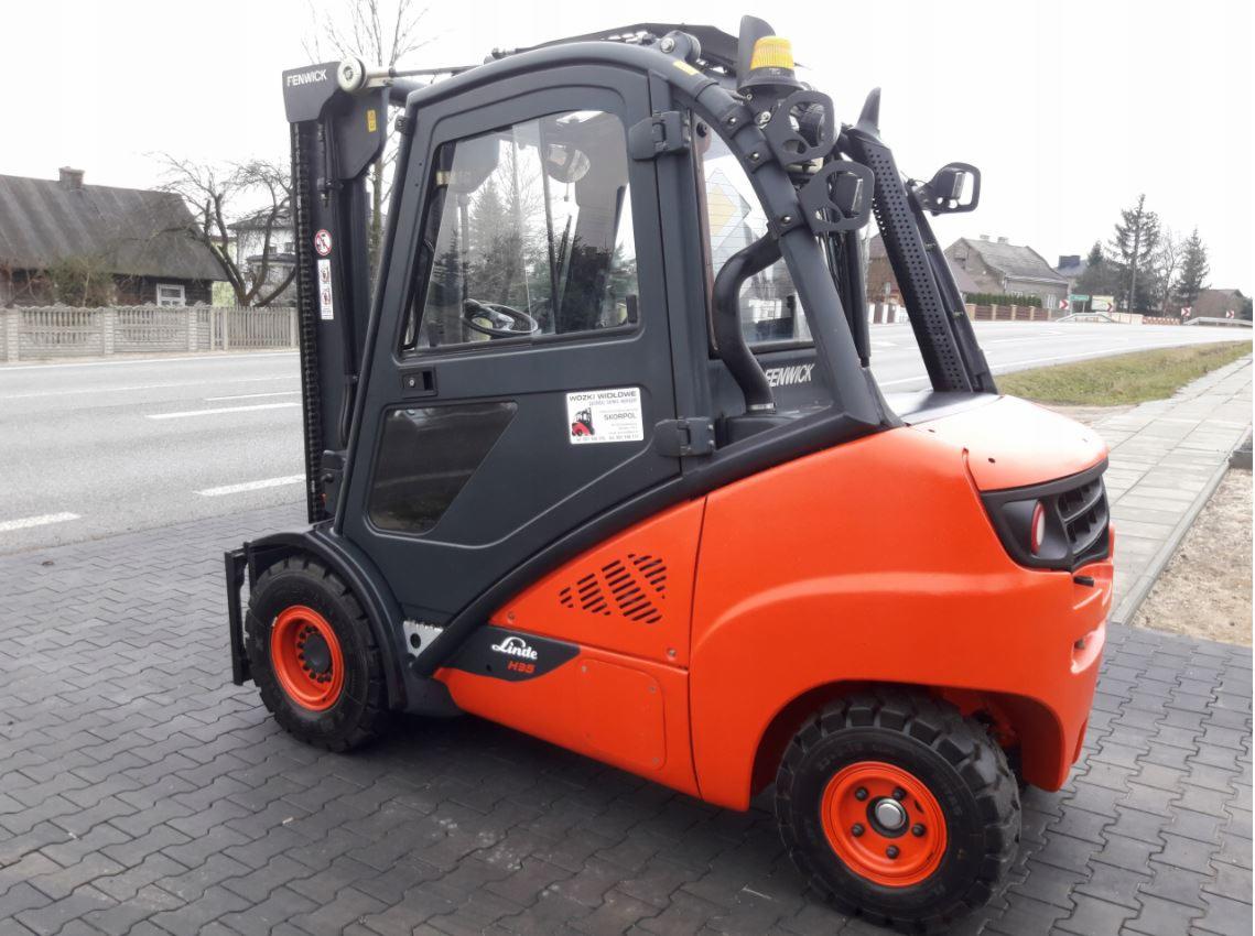 Pomarańczowo-szary wózek widłowy Linde H35 z kabiną na tle chodnika i drogi, widoczny z boku.