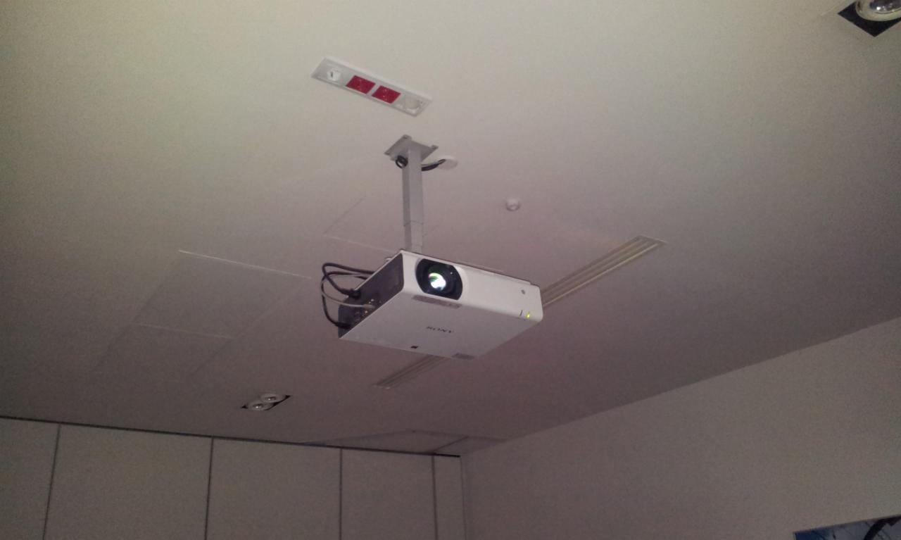 Zamontowany projektor Sony na suficie podwieszanym z widocznymi kablami i elementami mocującymi.