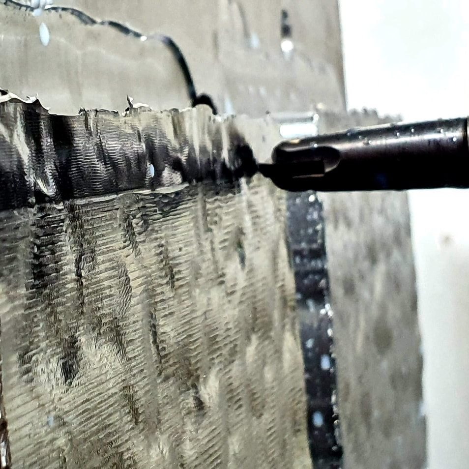 Frezarka CNC obrabia metal, widoczne ślady frezowania i chłodziwo.