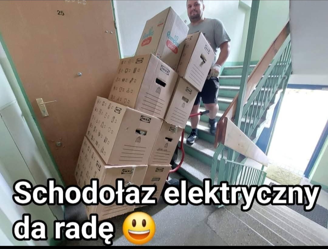 Mężczyzna w rękawicach transportuje kartony Ikea po schodach za pomocą elektrycznego schodołaza.