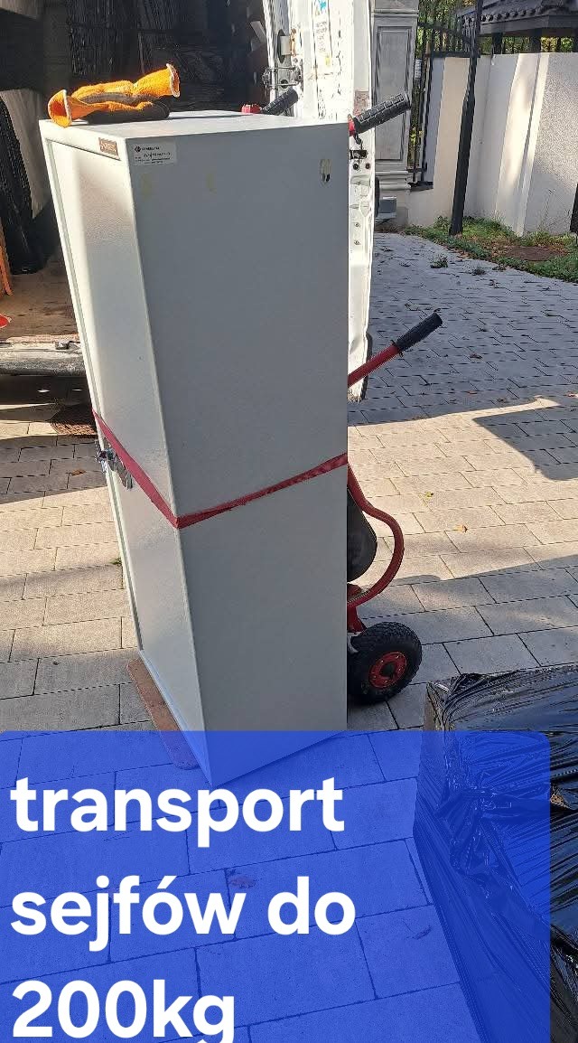 Transport sejfu na wózku transportowym, zabezpieczonego czerwoną taśmą, przygotowanego do załadunku do busa. Widoczne rękawice robocze na sejfie.