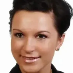 Portret kobiety z krótkimi, ciemnymi włosami, delikatnym makijażem i subtelną biżuterią, uśmiechająca się do kamery.