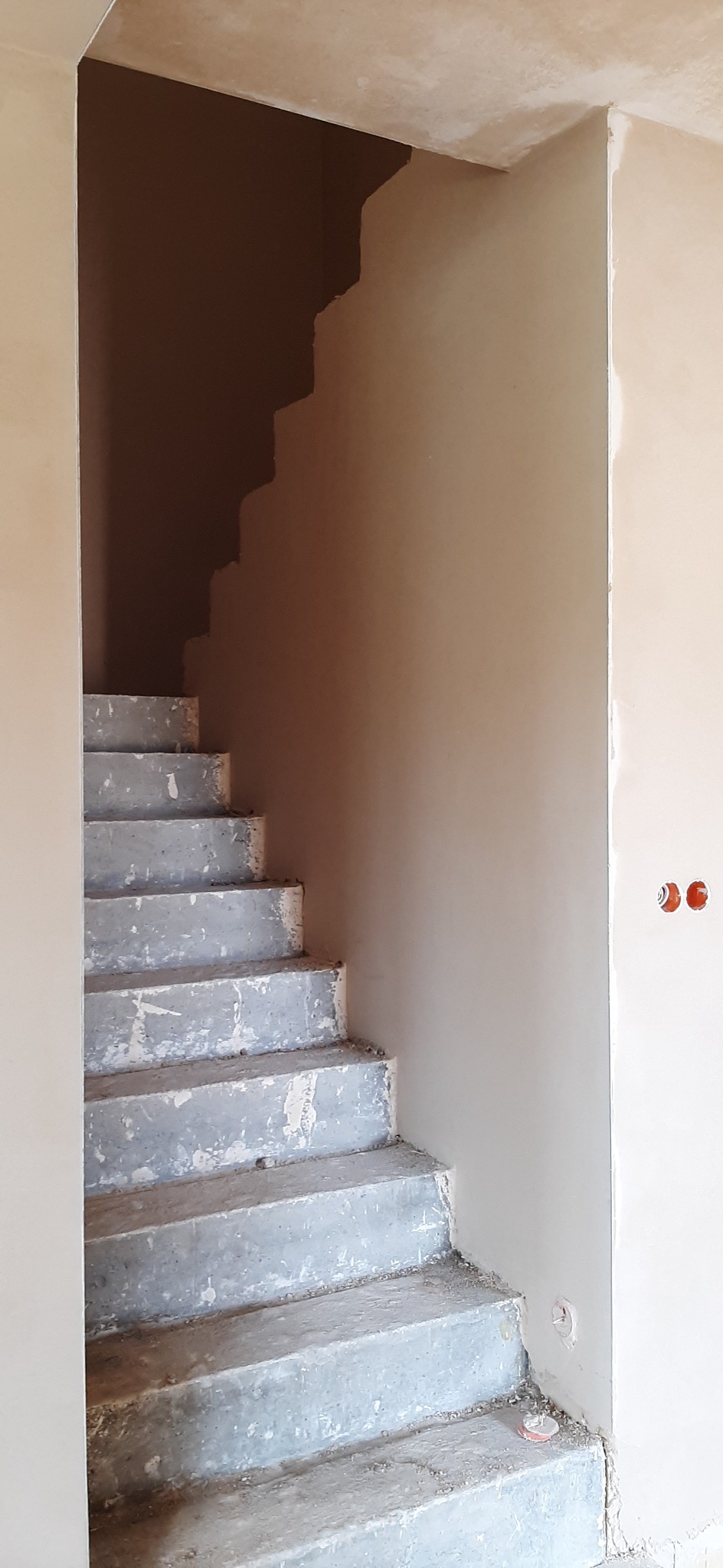 Surowe schody betonowe w trakcie prac wykończeniowych we Wrocławiu, ściany przygotowane pod malowanie, widoczne puszki elektryczne.