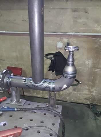 Spawanie rur w warsztacie w Kamiennej Górze, widoczne świeże spawy na metalowej konstrukcji, na stole spawalniczym leży spawarka.