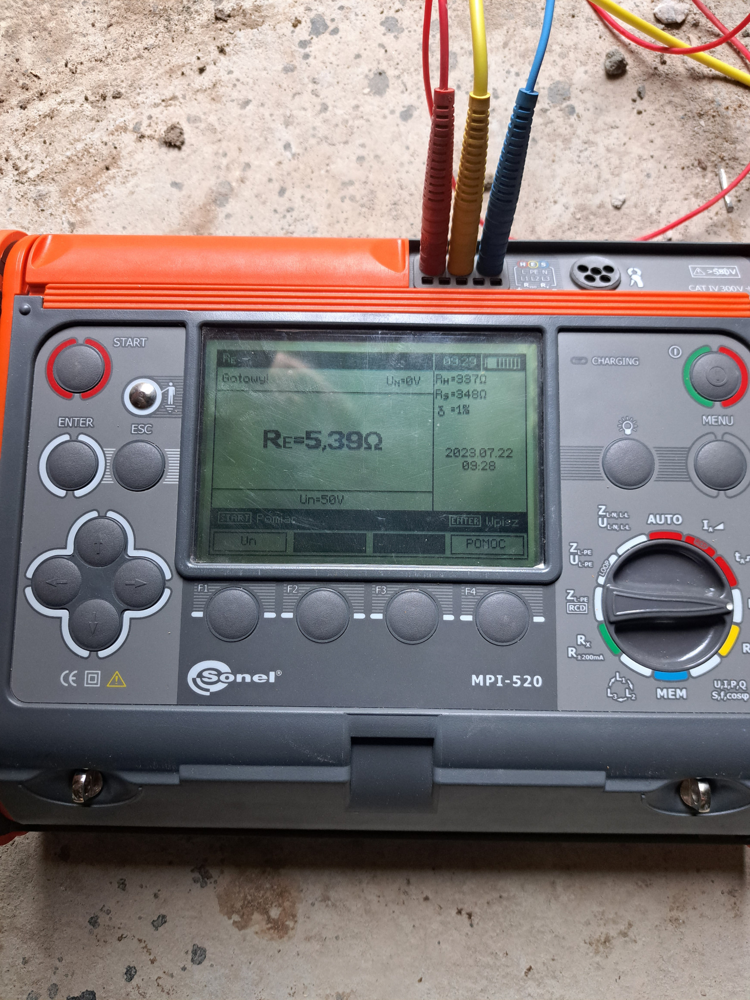Miernik instalacji elektrycznych Sonel MPI-520 z podłączonymi przewodami pomiarowymi, wyświetlający wynik pomiaru rezystancji uziemienia Re=5,39Ω na tle betonowej posadzki.