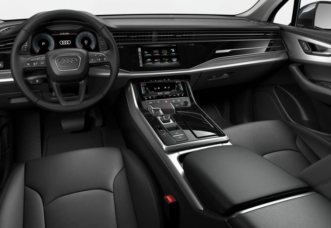 Wnętrze samochodu marki Audi z czarną skórzaną tapicerką, widok na deskę rozdzielczą z ekranem dotykowym i kierownicę z logo Audi.