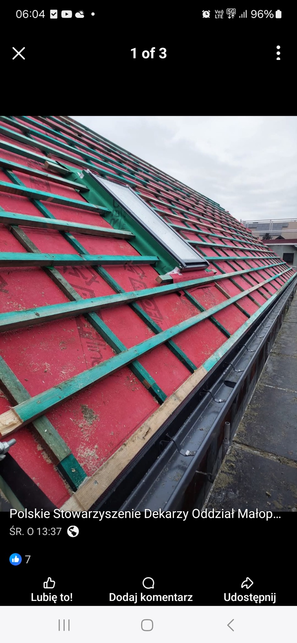 Dach z oknem połaciowym w trakcie budowy: czerwona membrana, drewniane łaty w kolorze turkusowym, czarna rynna. Widok z góry na ukośną konstrukcję.