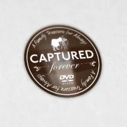 Okrągła brązowa naklejka z napisem 'Captured forever' oraz grafiką kamery na trójnogu i tekstem 'A Family Treasure for Always' otaczającym obwód, wskazująca na pamiątkowe nagrania wideo na DVD.
