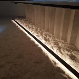 Instalacje elektryczne Łukasz Piekut - Oświetlenie LED pod schodami, listwa przypodłogowa z wbudowanym światłem, surowy beton, minimalistyczny design.