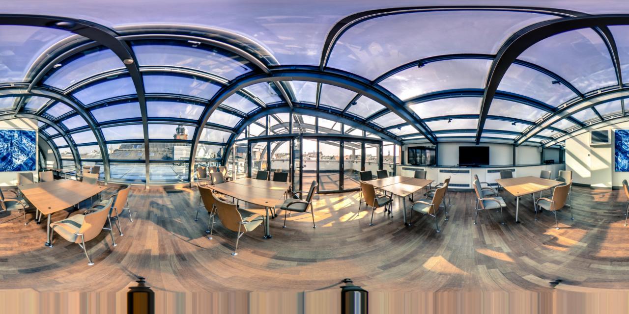 Panoramiczne ujęcie jasnego biura z drewnianą podłogą, szklanym dachem i widokiem na miasto