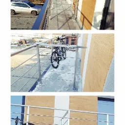 Balkon z nowoczesną, metalową balustradą ze stali nierdzewnej, widok na osiedle domów jednorodzinnych, rower oparty o poręcz.