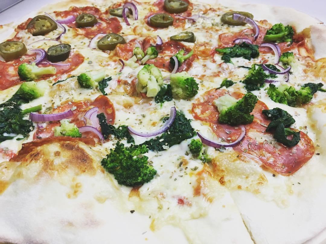 Pizza z salami, brokułami, szpinakiem, czerwoną cebulą i papryczkami jalapeno.