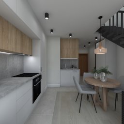 Projekt Studio Dagmara Hus - Wizualizacja nowoczesnej kuchni z drewnianymi i białymi szafkami, szarym blatem, płytą indukcyjną, piekarnikiem, okrągłym stołem jadalnym z szarymi krzesłami i schodami w tle.