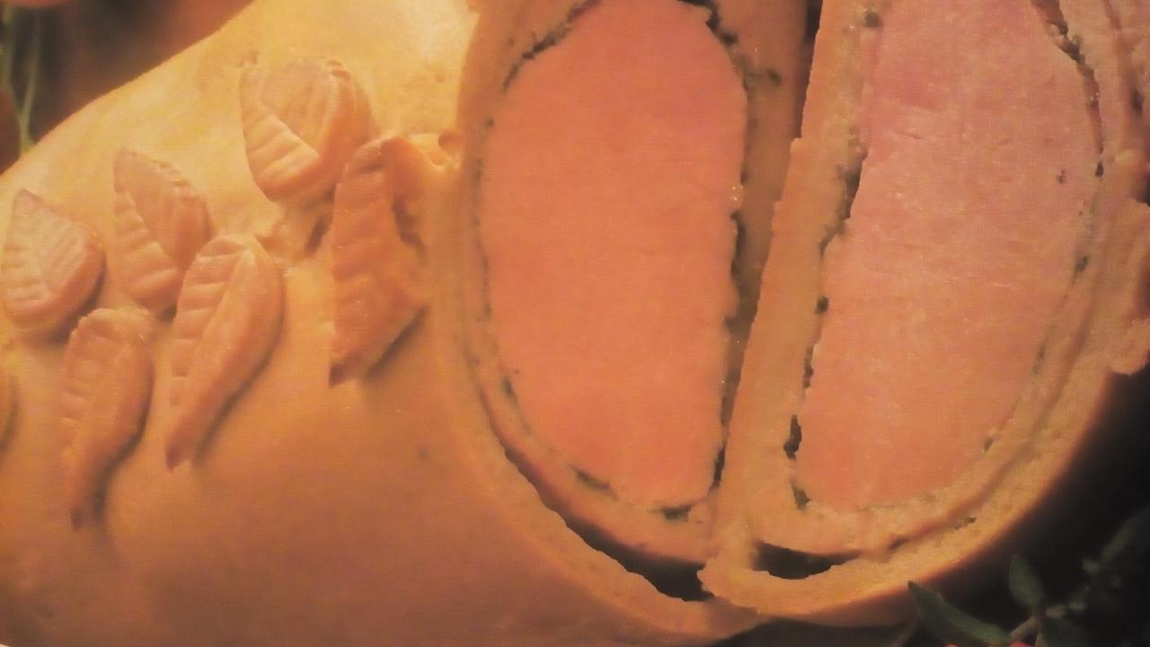 Pasztet pieczony w cieście francuskim, udekorowany ciastkami w kształcie liści, przekrojony na pół.