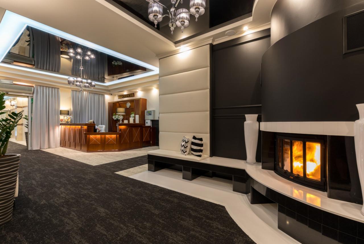 Eleganckie wnętrze hotelowe z recepcją, kominkiem z paleniskiem i dekoracyjnym oświetleniem sufitowym.