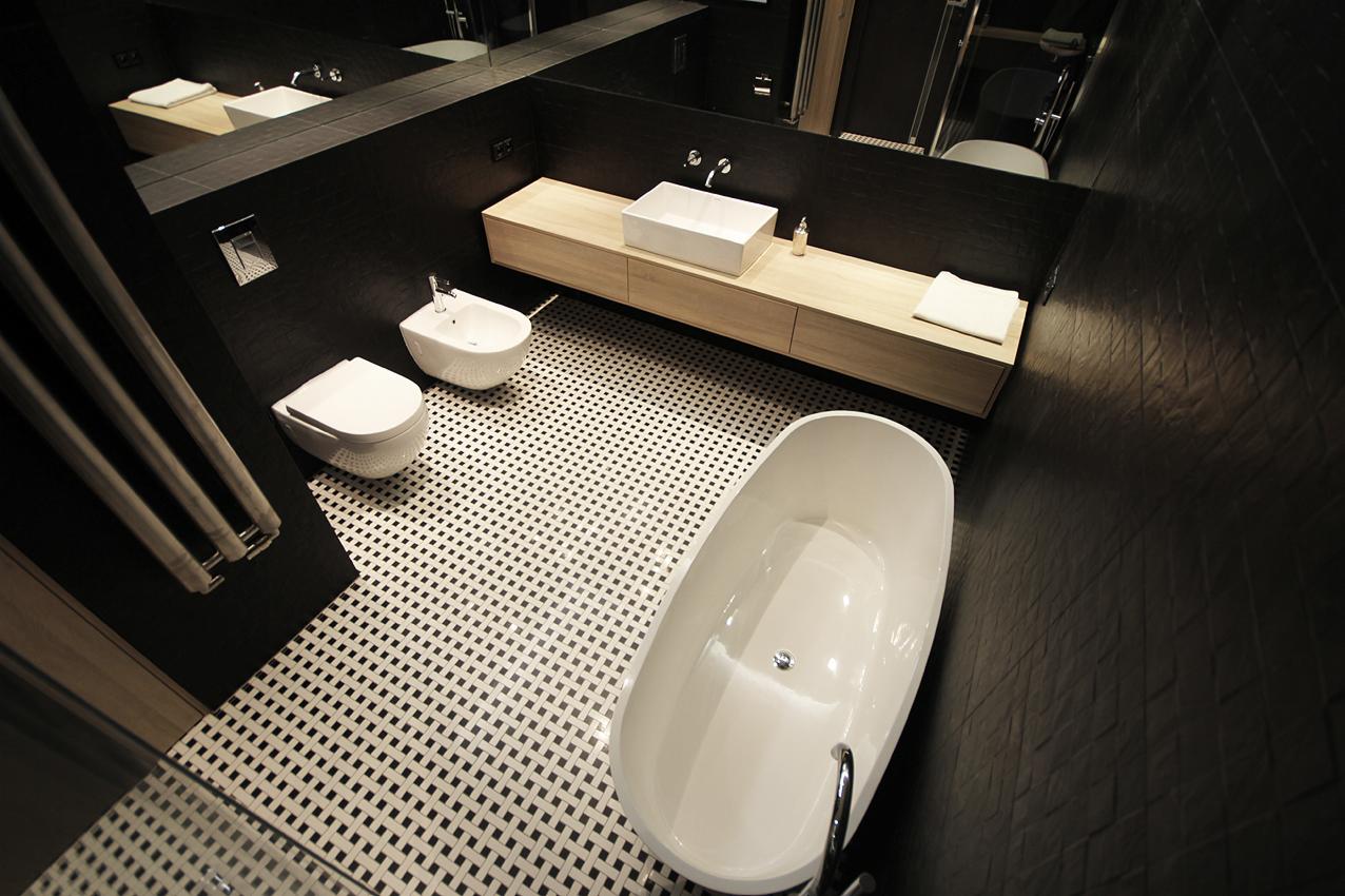 Nowoczesna łazienka z czarnymi ścianami, białą armaturą i geometryczną podłogą w kratkę widziana z góry.