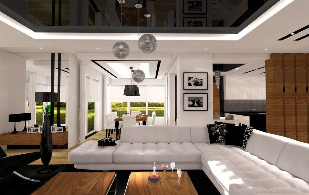 Nowoczesny salon z białym narożnikiem, drewnianymi stolikami kawowymi i dekoracyjnymi lampami w kształcie kul dyskotekowych, widok na jadalnię i kuchnię w tle.