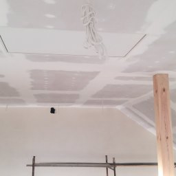 Tadeusz Trojan - Skośny sufit poddasza po montażu płyt gipsowo-kartonowych, widoczne łączenia przygotowane do szpachlowania. Podpory drewniane i fragment rusztowania.