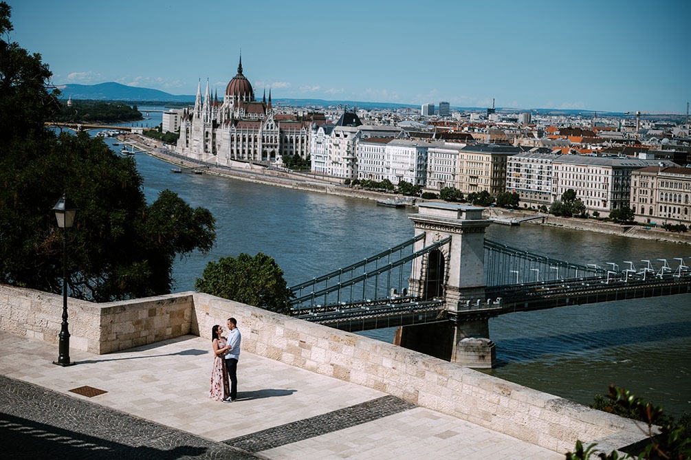 Para obejmująca się na tle panoramy Budapesztu z Parlamentem i mostem łańcuchowym, widok z góry, słoneczny dzień.