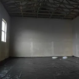 Surowe wnętrze z przygotowanymi ścianami pod tynk maszynowy, podłoga zabezpieczona folią, widoczne dwa białe kręgi węży.