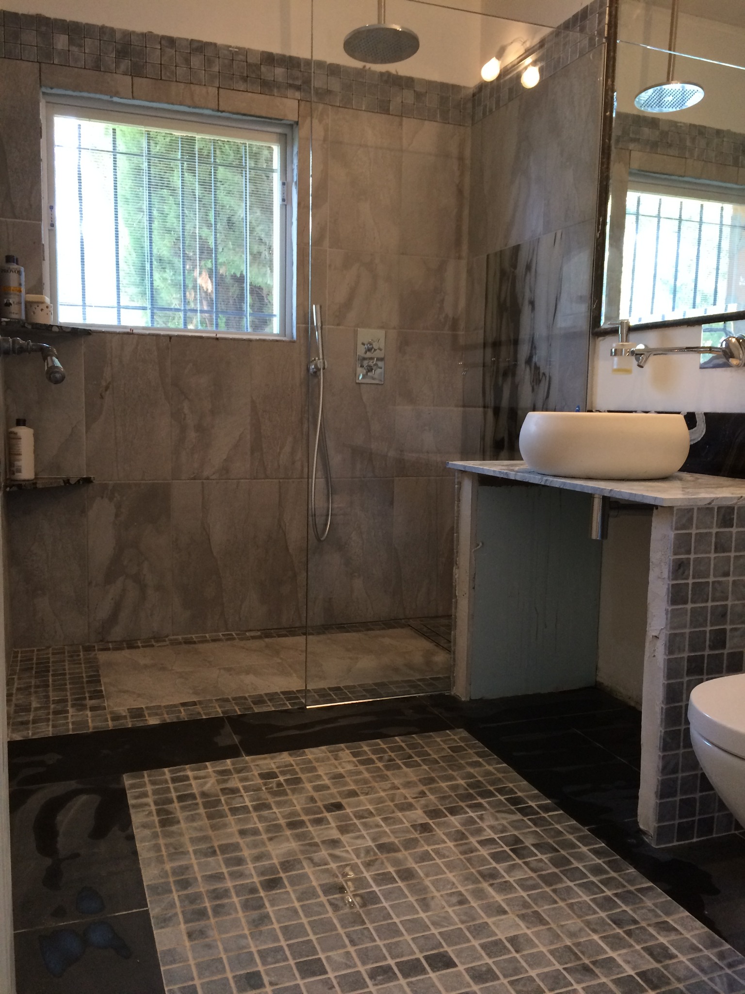 Wykończona łazienka w Lublinie z kabiną prysznicową typu walk-in, umywalką nablatową i mozaiką na podłodze oraz ścianach.