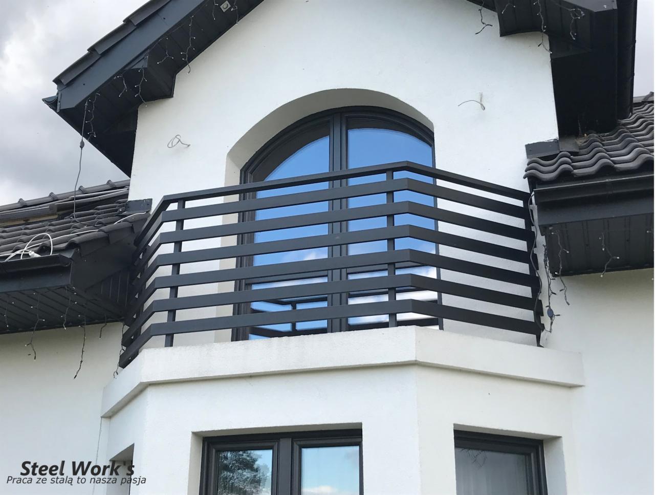 Nowoczesna, czarna balustrada balkonowa z poziomych profili, zamontowana na białym budynku z oknem łukowym, widok z dołu.