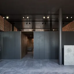 Wnętrze biura z surowymi ceglanymi ścianami, betonową podłogą i recepcją z logo Instytutu Pamięci Narodowej, oświetlone punktowymi lampami.