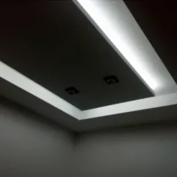 Sufit podwieszany z oświetleniem LED wzdłuż krawędzi i dwoma punktowymi lampami, widok z narożnika pomieszczenia.