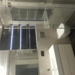 Nowoczesna łazienka z kabiną prysznicową ze szklaną ścianką, wiszącą toaletą i umywalką w zabudowie, wykończona płytkami w odcieniach beżu i brązu, z grzejnikiem drabinkowym.