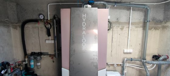 Zainstalowany system Hydraloop w pomieszczeniu technicznym z widocznymi rurami, filtrami i manometrem na surowym betonowym tle.