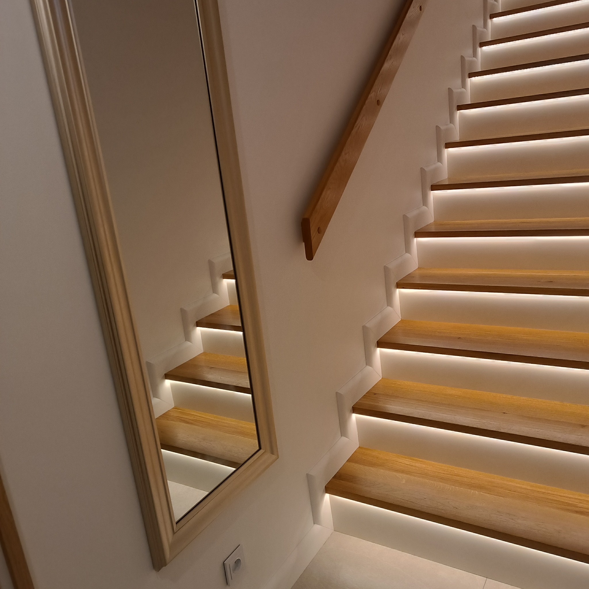 Nowoczesne schody drewniane z podświetleniem LED, widoczne odbicie schodów w lustrze, minimalistyczny design.