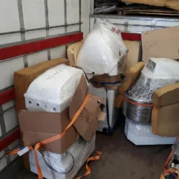 Wnętrze busa z zabezpieczonymi maszynami piekarniczymi, owiniętymi folią i spiętymi pasami transportowymi, gotowymi do transportu w Wołominie.