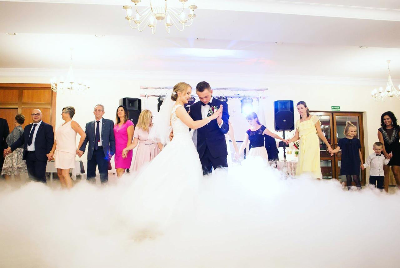 Para młoda w tańcu otoczona gośćmi, niski dym, nagłośnienie po bokach, oświetlenie sceniczne.