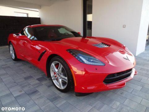 Czerwony sportowy samochód Corvette zaparkowany w garażu z szarymi płytkami podłogowymi.