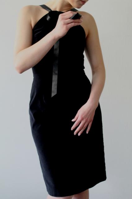 Czarna, dopasowana sukienka z aksamitu z ozdobną wstążką i kokardą, prezentowana na osobie.