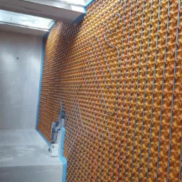 Montaż rur w systemie ogrzewania podłogowego na panelach izolacyjnych w surowym wnętrzu z oświetleniem sufitowym.