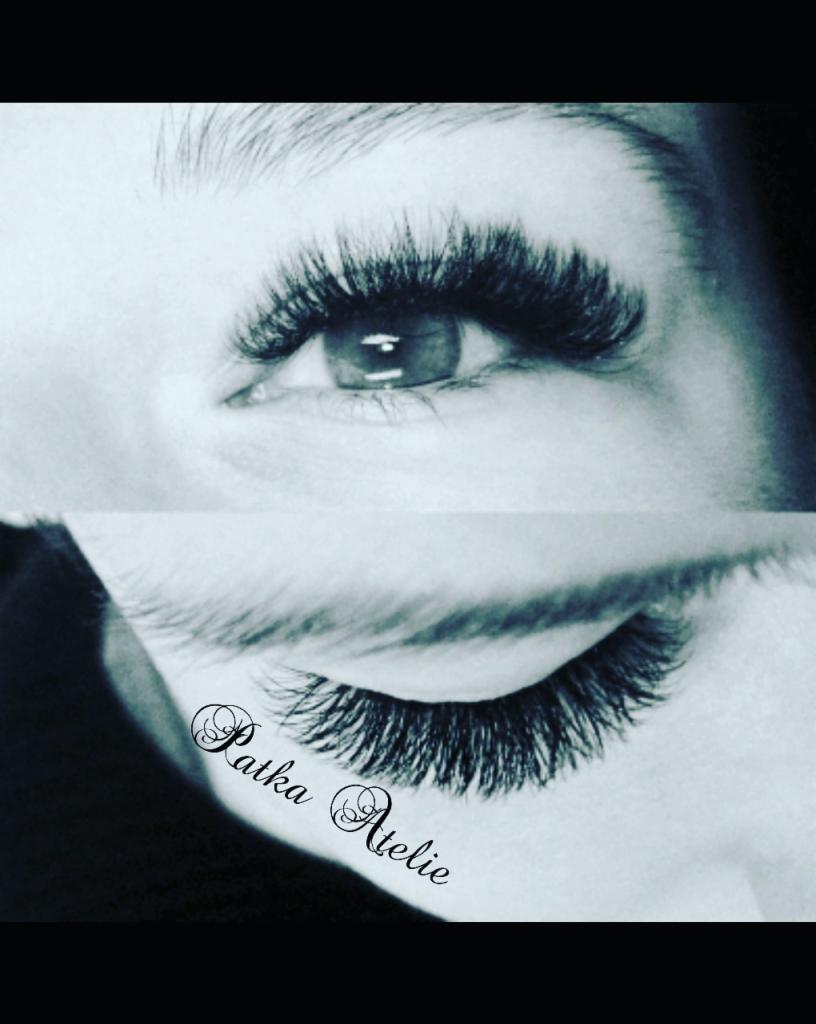 Zbliżenie na oko z gęstymi, przedłużonymi rzęsami w odcieniach szarości, z widocznym logo 'Patka Atelie' na dolnej powiece.